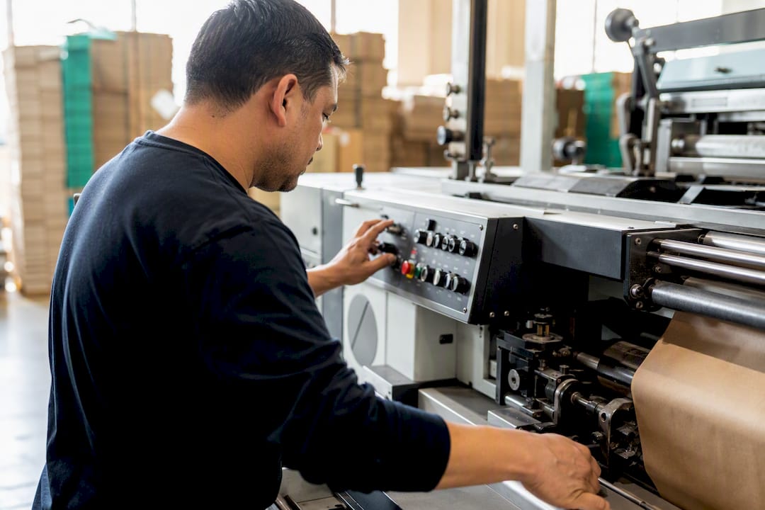 Hands operating paper bag printing press