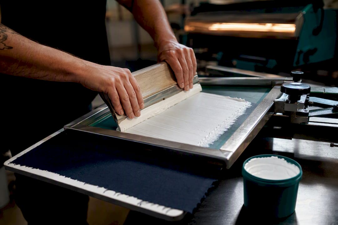 Operator printing white underbase on dark fabric