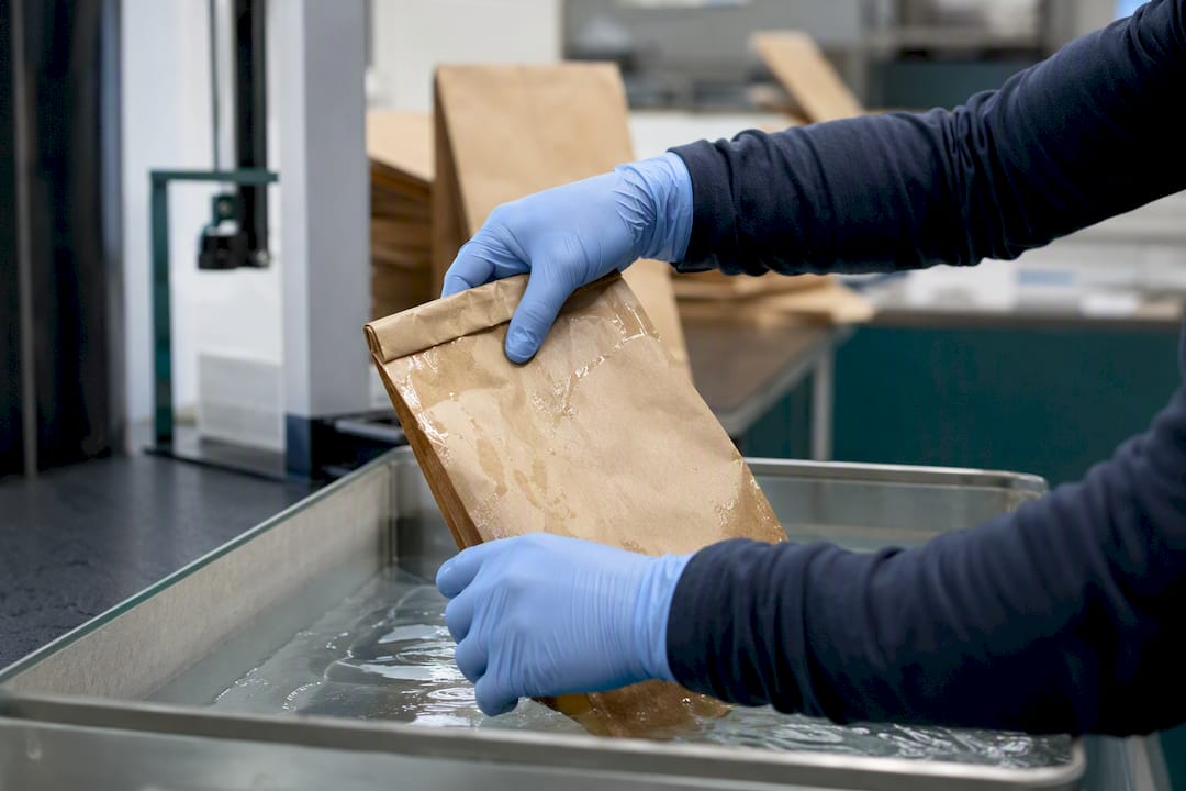 Hands testing wet strength of paper bag