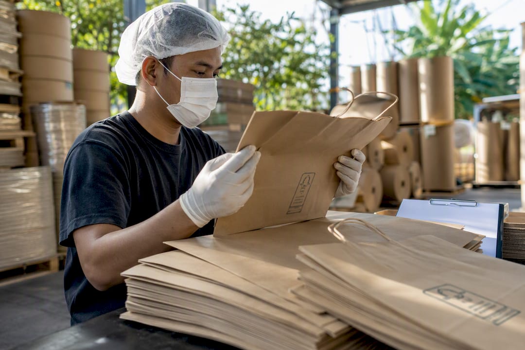 Hands arranging FSC-certified paper bags on conveyor