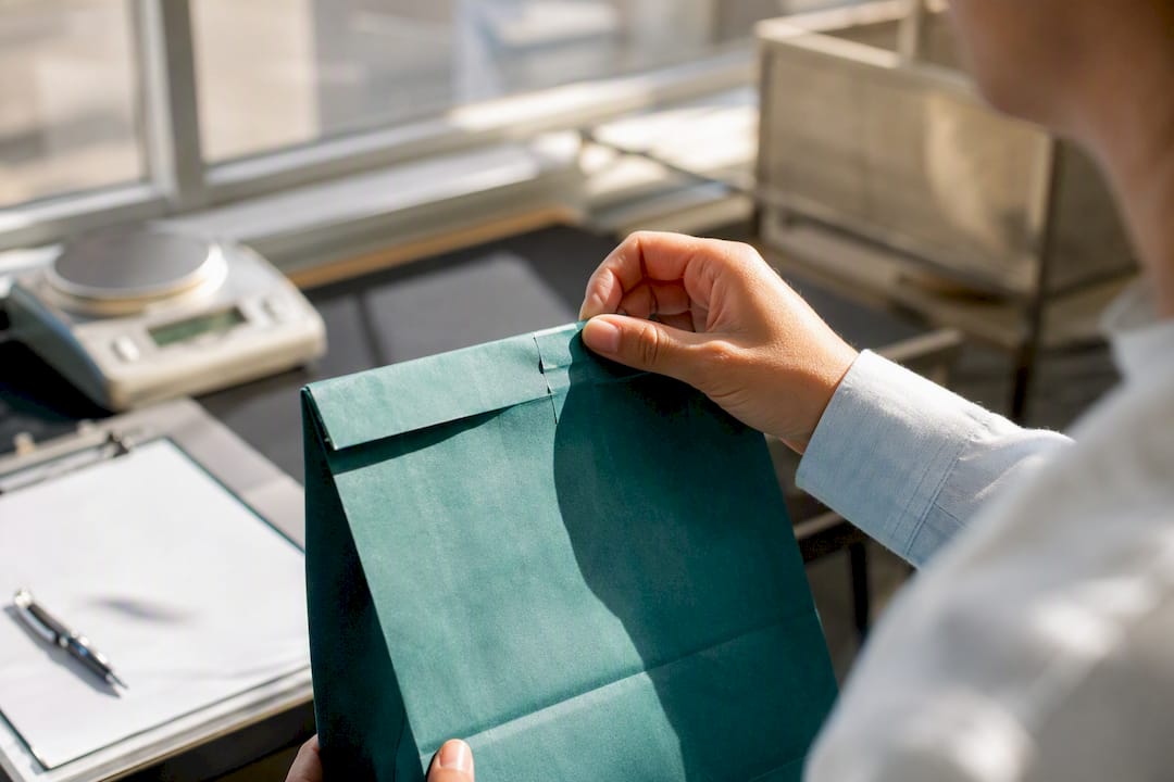 Hand inspecting tamper-evident paper bag seal